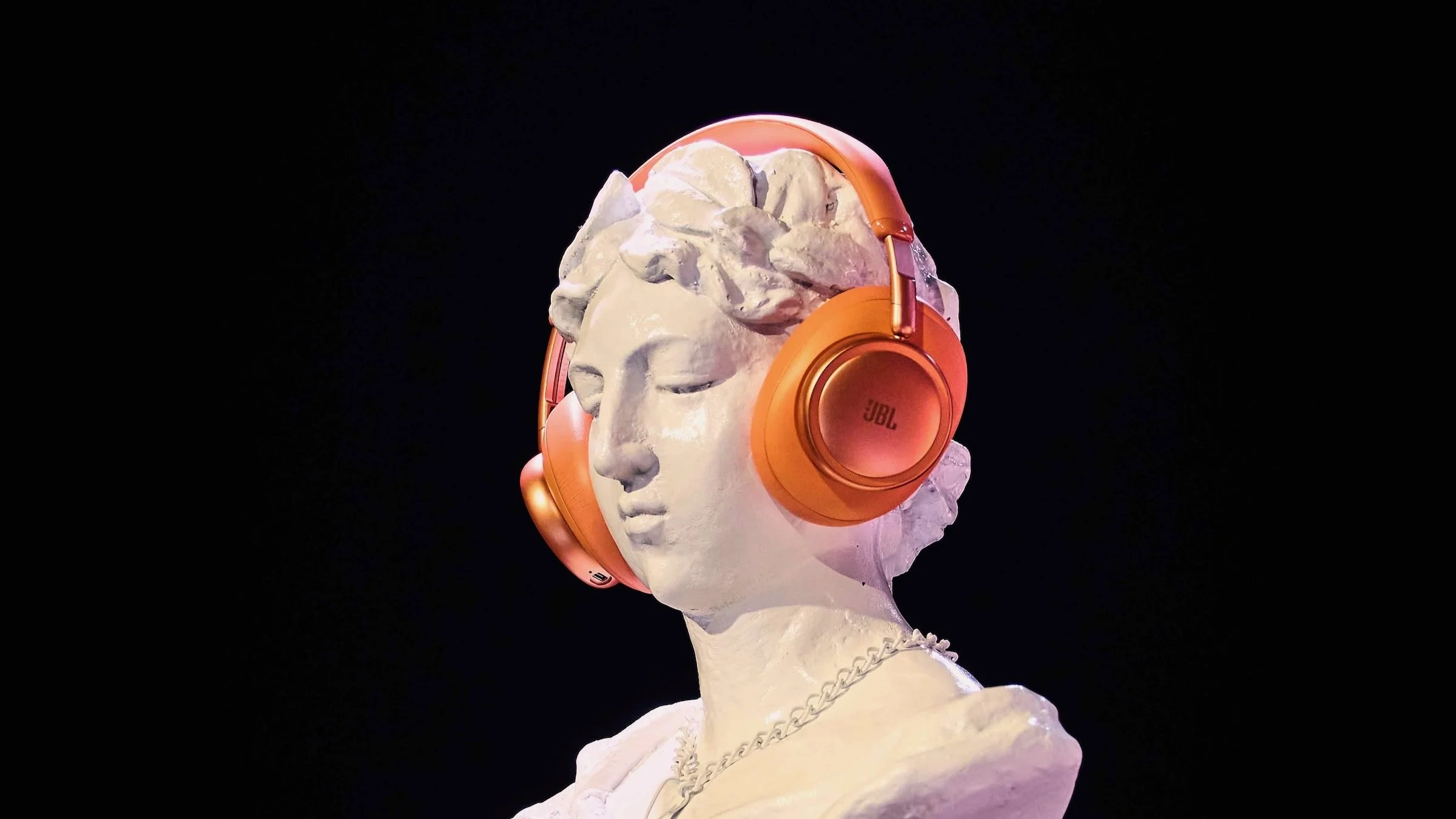 orange jbl live headphones on a roman statue bust